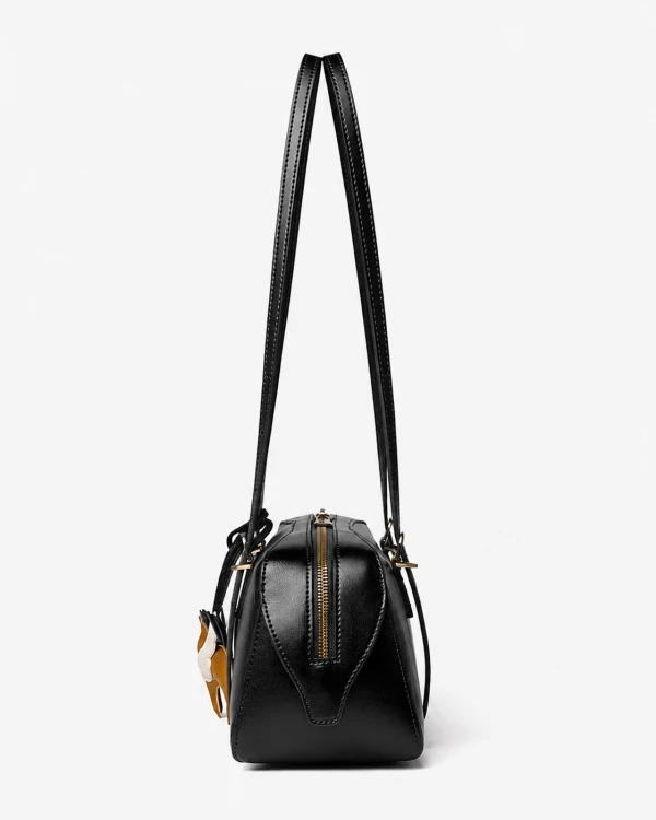 Czarna skórzana torebka damska typu baguette o wydłużonej, eleganckiej formie inspirowanej fasonem bowling bag łączy minimalistyczny design z subtelnym retro charakterem. Profil.