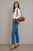 Skórzana torebka damska w eleganckim kasztanowym odcieniu brązu. Kształt torebki nawiązuje do klasycznych modeli bowling bag oraz baguette. Modelka