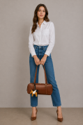 Skórzana torebka damska w eleganckim kasztanowym odcieniu brązu. Kształt torebki nawiązuje do klasycznych modeli bowling bag oraz baguette. Modelka