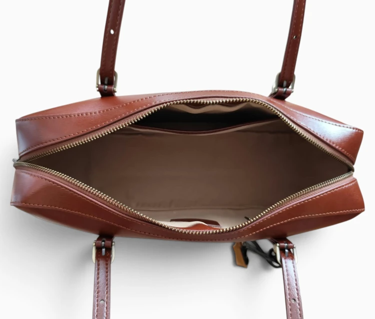 Skórzana torebka damska w eleganckim kasztanowym odcieniu brązu. Kształt torebki nawiązuje do klasycznych modeli bowling bag oraz baguette. Wnętrze.