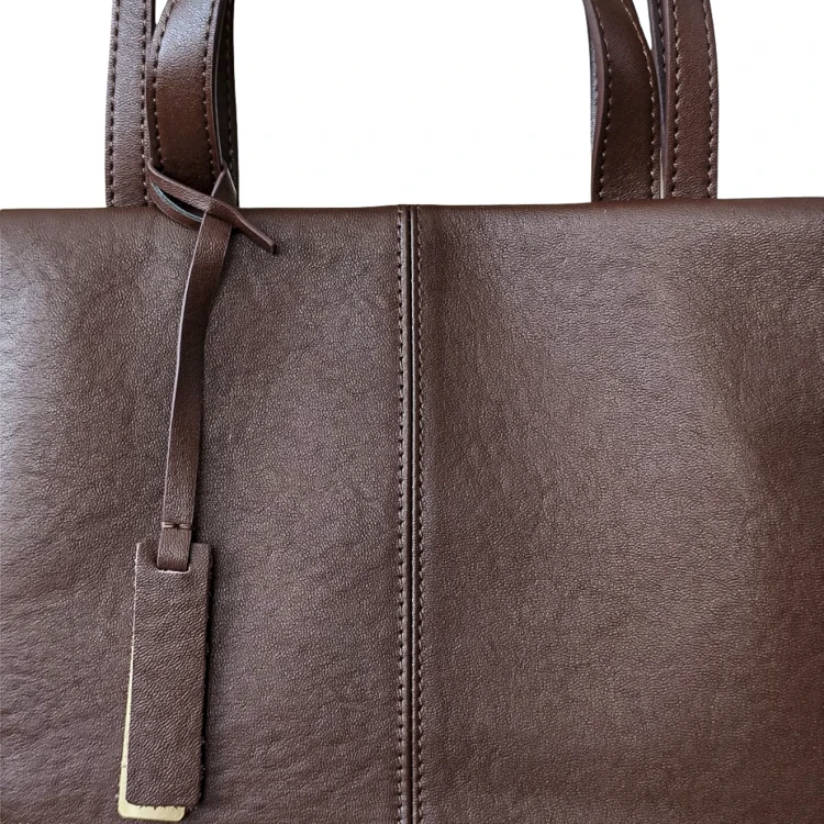 Damska skórzana torebka ciemnobrązowa typu shopper. Detal, zawieszka.